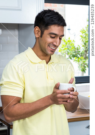 Smiling man in kitchen enjoying morning coffee, feeling relaxed and content Smiling man in kitchen enjoying morning coffee, feeling relaxed and content 126485239