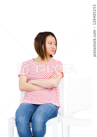 Young woman in striped shirt sitting with crossed arms, looking away thoughtfully Young woman in striped shirt sitting with crossed arms, looking away thoughtfully 126485253