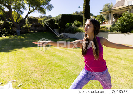 Young woman practicing yoga in backyard, focusing on balance and relaxation, copy space 126485271