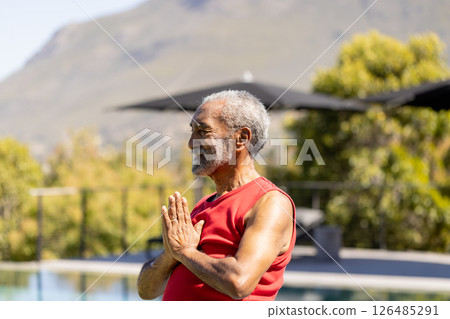 Senior man practicing yoga by pool, enjoying peaceful outdoor relaxation, copy space 126485291