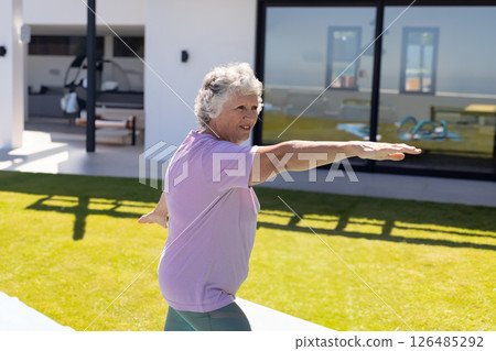 Senior woman practicing yoga outdoors on sunny day, stretching arms on mat, copy space Senior woman practicing yoga outdoors on sunny day, stretching arms on mat, copy space 126485292