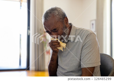 Elderly man sitting at home, wiping tears with tissue, feeling emotional, copy space Elderly man sitting at home, wiping tears with tissue, feeling emotional, copy space 126485299