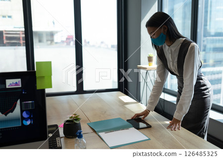 Businesswoman in mask organizing documents and smartphone at modern office desk, copy space Businesswoman in mask organizing documents and smartphone at modern office desk, copy space 126485325