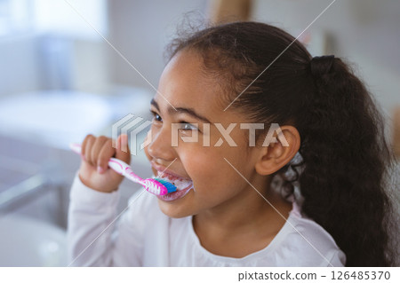 Young girl brushing teeth at home, smiling and enjoying morning routine, copy space Young girl brushing teeth at home, smiling and enjoying morning routine, copy space 126485370