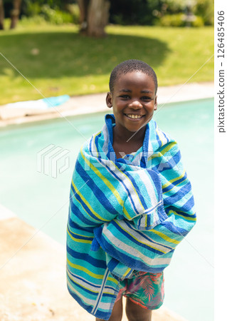 Smiling boy wrapped in colorful towel enjoying sunny day by pool, copy space Smiling boy wrapped in colorful towel enjoying sunny day by pool, copy space 126485406