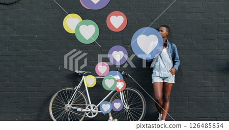 Young woman leaning on bicycle against wall with colorful heart icons floating Young woman leaning on bicycle against wall with colorful heart icons floating 126485854