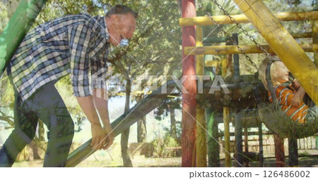 Father playing with child on playground slide, both enjoying sunny day outdoors 126486002