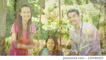 In garden, happy family swinging together, smiling and spending quality time In garden, happy family swinging together, smiling and spending quality time 126486005