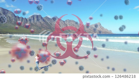 Person walking on beach with virus symbols overlaying scenic mountain view 126486218