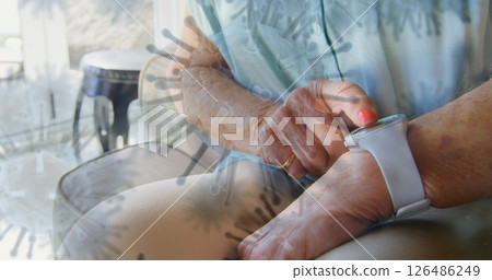 Elderly person checking smartwatch at home, focusing on health monitoring Elderly person checking smartwatch at home, focusing on health monitoring 126486249
