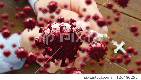Hands holding cross surrounded by virus particles, symbolizing hope and faith 126486253