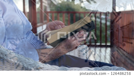 Elderly person reading book on porch, relaxing during pandemic lockdown 126486258