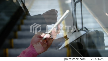 Business professional using tablet and smartphone while commuting on escalator Business professional using tablet and smartphone while commuting on escalator 126486259