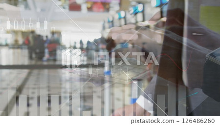 Businessman analyzing financial data on tablet with airport terminal in background Businessman analyzing financial data on tablet with airport terminal in background 126486260