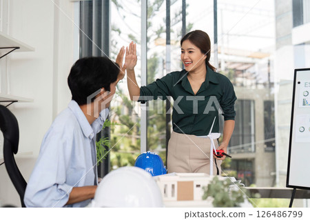 Positive Interaction in Sustainable Design. Colleagues sharing ideas and high-fiving in a modern office. 126486799