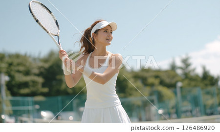 A woman in white clothing enjoying tennis under the blue sky A woman in white clothing enjoying tennis under the blue sky 126486920