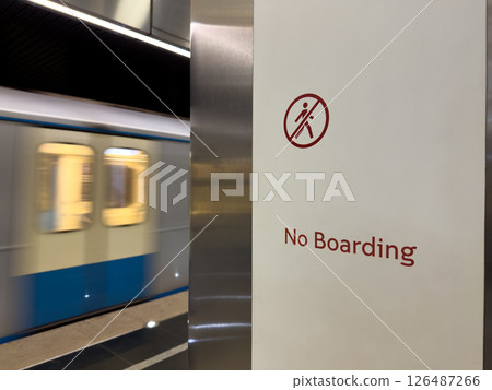 High speed subway train passing by No Boarding sign in modern underground station. Urban transit safety, restriction and public transportation concept with motion blur effect High speed subway train passing by No Boarding sign in modern underground station. Urban transit safety, restriction and public transportation concept with motion blur effect 126487266
