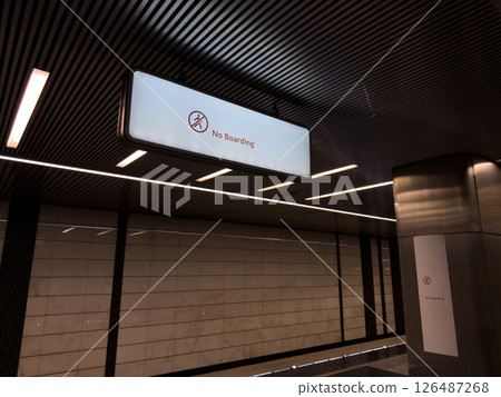 Illuminated No Boarding sign hanging from the ceiling in modern metro station with stylish architectural design. Clear prohibition message ensures passenger safety in public transport zones Illuminated No Boarding sign hanging from the ceiling in modern metro station with stylish architectural design. Clear prohibition message ensures passenger safety in public transport zones 126487268