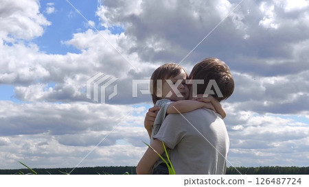 Loving, caring family, happy childhood. Boy in a field in a meadow runs towards brother. family spends time in nature, brothers hug. Brother's Day. little brother runs into the arms of older brother 126487724
