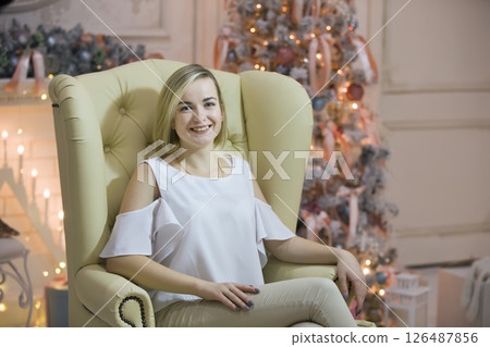 A young girl on the background of a Christmas tree.Girl in a leather chair A young girl on the background of a Christmas tree.Girl in a leather chair 126487856