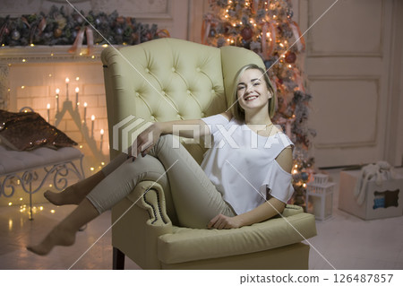 A young girl on the background of a Christmas tree.Girl in a leather chair 126487857