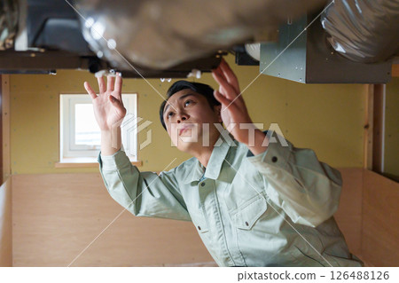 Male worker inspecting air conditioning Male worker inspecting air conditioning 126488126