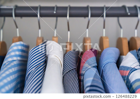 Neatly arranged men shirts hanging on wooden hangers in wardrobe. Minimalist clothing organization and classic male fashion concept 126488229