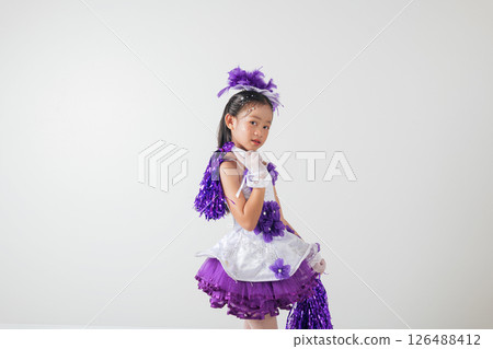 Little cheerleader girl in purple uniform with pom-poms, smiling joyfully. White studio background highlights her enthusiasm and team spirit. cheerleader kid Little cheerleader girl in purple uniform with pom-poms, smiling joyfully. White studio background highlights her enthusiasm and team spirit. cheerleader kid 126488412