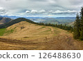 Mountain Trail Through Grassy Hills and Cloudy Sky 126488630