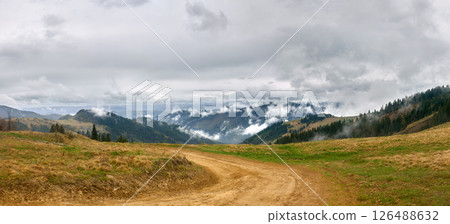 Winding Dirt Road Through Hills Toward Misty Mountains 126488632