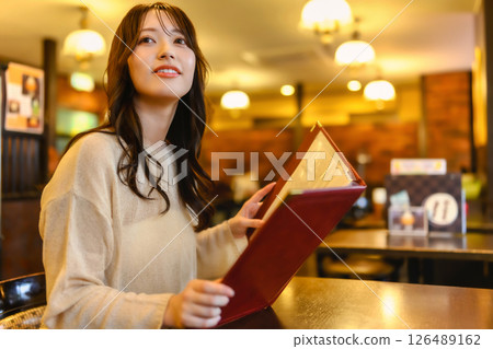Woman holding a menu book Woman holding a menu book 126489162