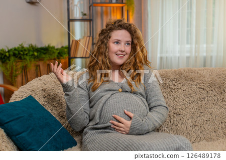 Pregnant young woman talking to belly at home gently touching bonding with baby emotional connection 126489178