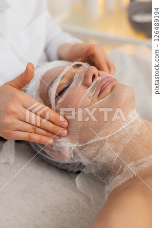 Woman receiving facial gauze wrap for carboxytherapy in cosmetology skin covered with serum moisture Woman receiving facial gauze wrap for carboxytherapy in cosmetology skin covered with serum moisture 126489194