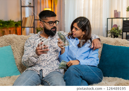 Indian family couple man woman planning expenses with cash and smartphone discussing shopping salary 126489195