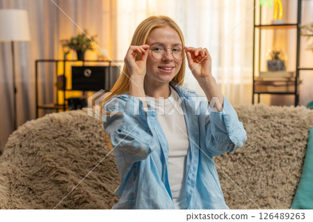 Young woman stylish glasses at home, confident look, sofa pose, vision aid, modern image enhancement 126489263