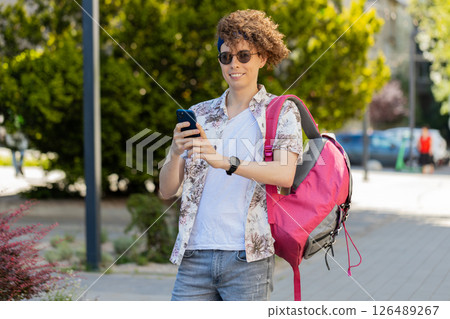 Tourist man using smartphone typing texting social media messages e-mail looking for a way on map Tourist man using smartphone typing texting social media messages e-mail looking for a way on map 126489267