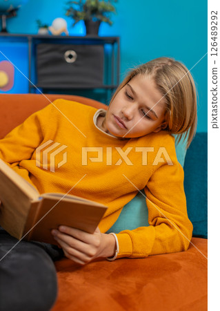 Teenager boy reading book, enthusiastically flipping pages, thoughtfully looking up, lying on sofa Teenager boy reading book, enthusiastically flipping pages, thoughtfully looking up, lying on sofa 126489292