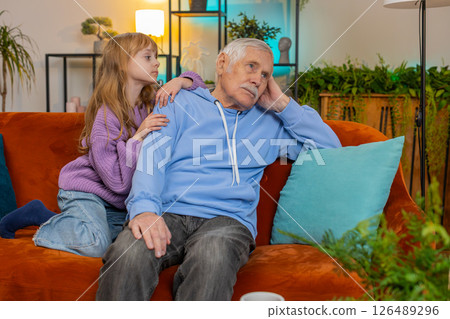 Loving worried kind girl granddaughter consoling sad crying grandfather helping with problem at home 126489296