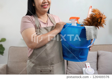 Cleaning and Home Care. A woman prepares for cleaning by holding a bucket filled with cleaning supplies. 126489376