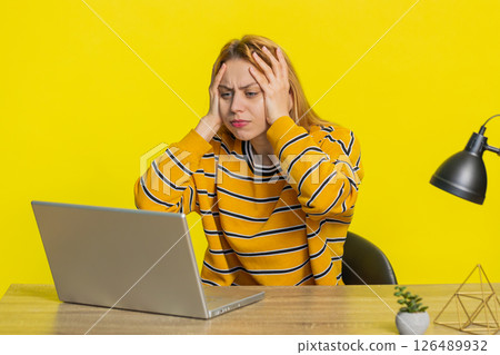 Woman using laptop surprised by bad news, fortune loss, game fail, lottery results sitting at table 126489932