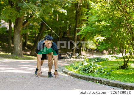 Asian athletic sport motivated runner man training, preparing to run race marathon in morning park Asian athletic sport motivated runner man training, preparing to run race marathon in morning park 126489938