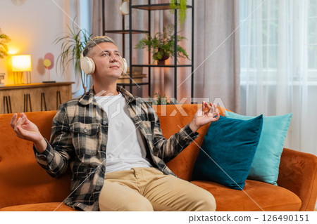 Man listening music, breathes deeply meditating with concentrated thoughts peaceful at home room 126490151