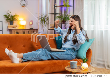 Surprised happy young woman using laptop computer, receive good news email message at home room Surprised happy young woman using laptop computer, receive good news email message at home room 126490158