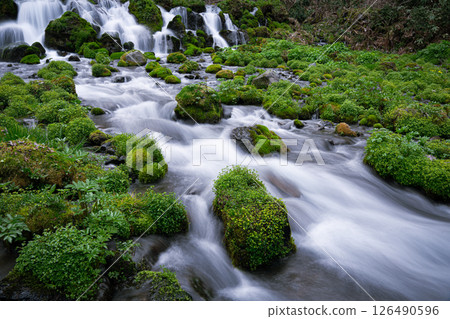 A clear stream flowing through moss-covered rocks 126490596
