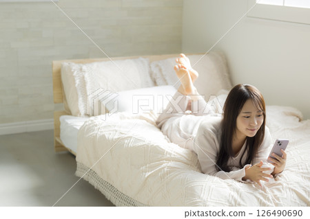 一名婦女在床上的看一個智能手機 126490690