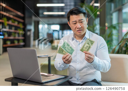 Upset businessman feeling worried about financial problems bad day sitting in modern office lobby 126490758
