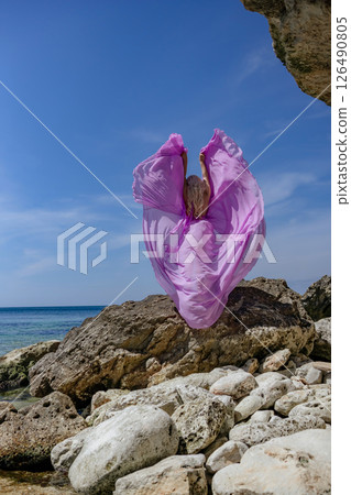 Plastic pollution ocean: Purple bag flies on rocky beach, littering the sea on a sunny day due to wind. Plastic pollution ocean: Purple bag flies on rocky beach, littering the sea on a sunny day due to wind. 126490805