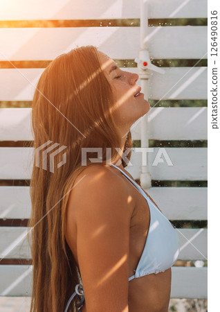 Woman Sunbathing Summer Beach: Outdoor portrait, happy woman enjoys sunlight, relaxing by white fence. 126490816