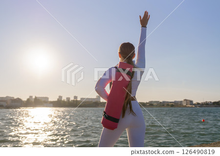 Yoga Woman Beach Sunrise: Woman practicing yoga on the beach at sunrise with a yoga mat. Yoga Woman Beach Sunrise: Woman practicing yoga on the beach at sunrise with a yoga mat. 126490819