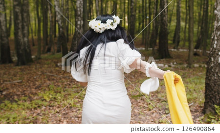 Caucasian middle aged woman in floral wreath running in the forest park looking at camera relaxation 126490864